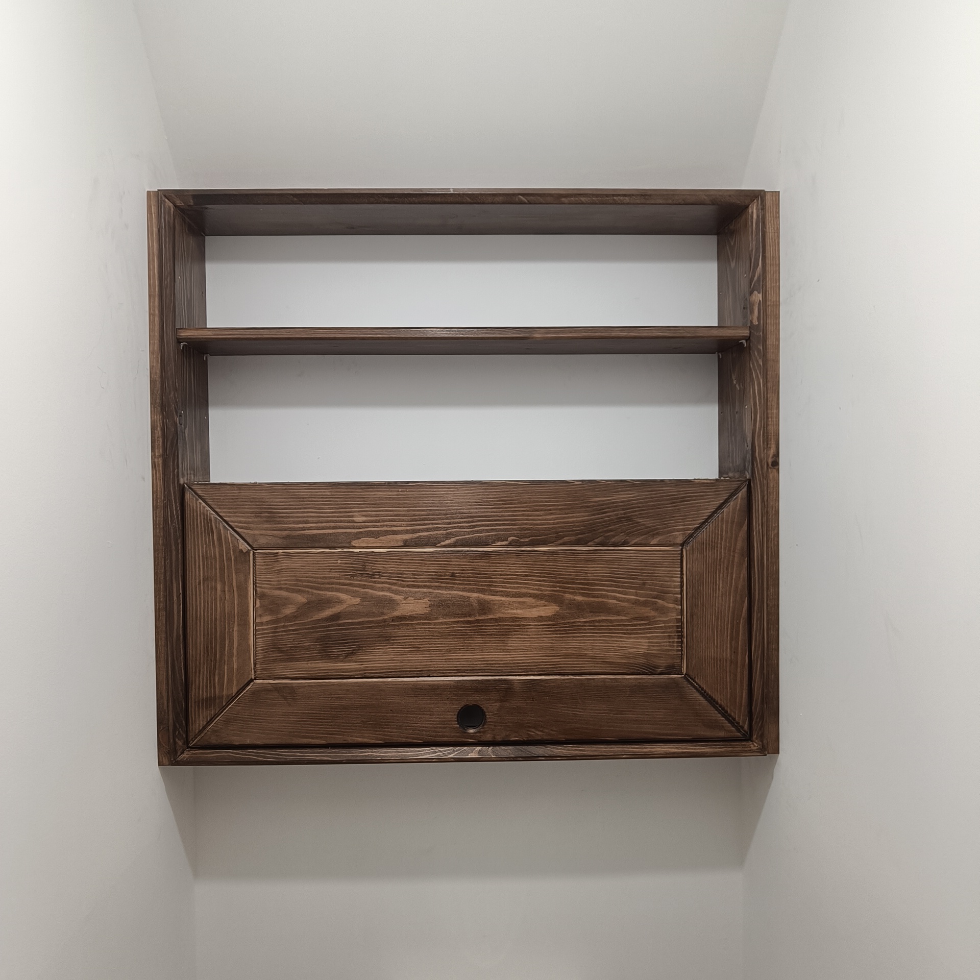A built in cabinet with shelving above and a door below