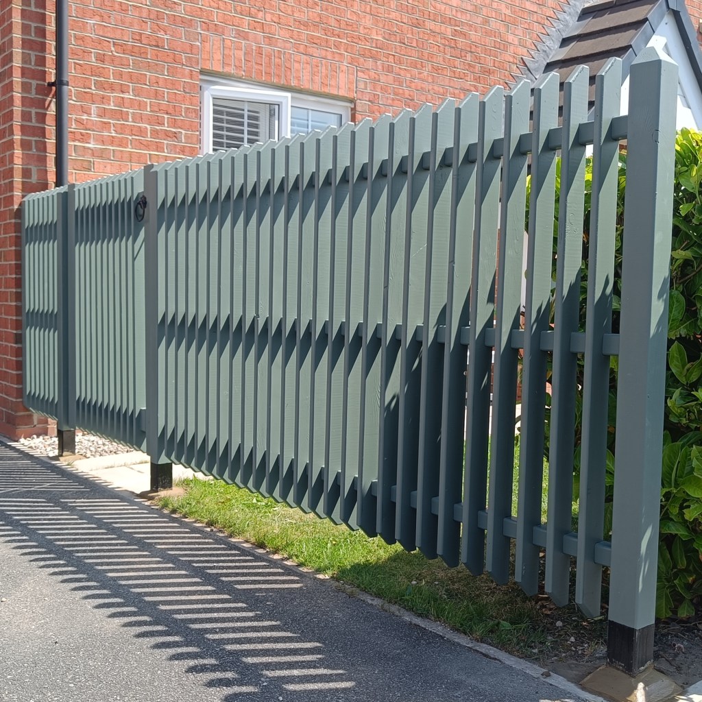 A picket fence and side gate for a front garden. Pickets are deep and rebated so that the fence rails sit within the depth of the pickets. Fence posts have been bitumen painted for longevity with a black band showing at the base of each fence post. The rest of the fence and gate are painted in Farrow & Ball Green Smoke