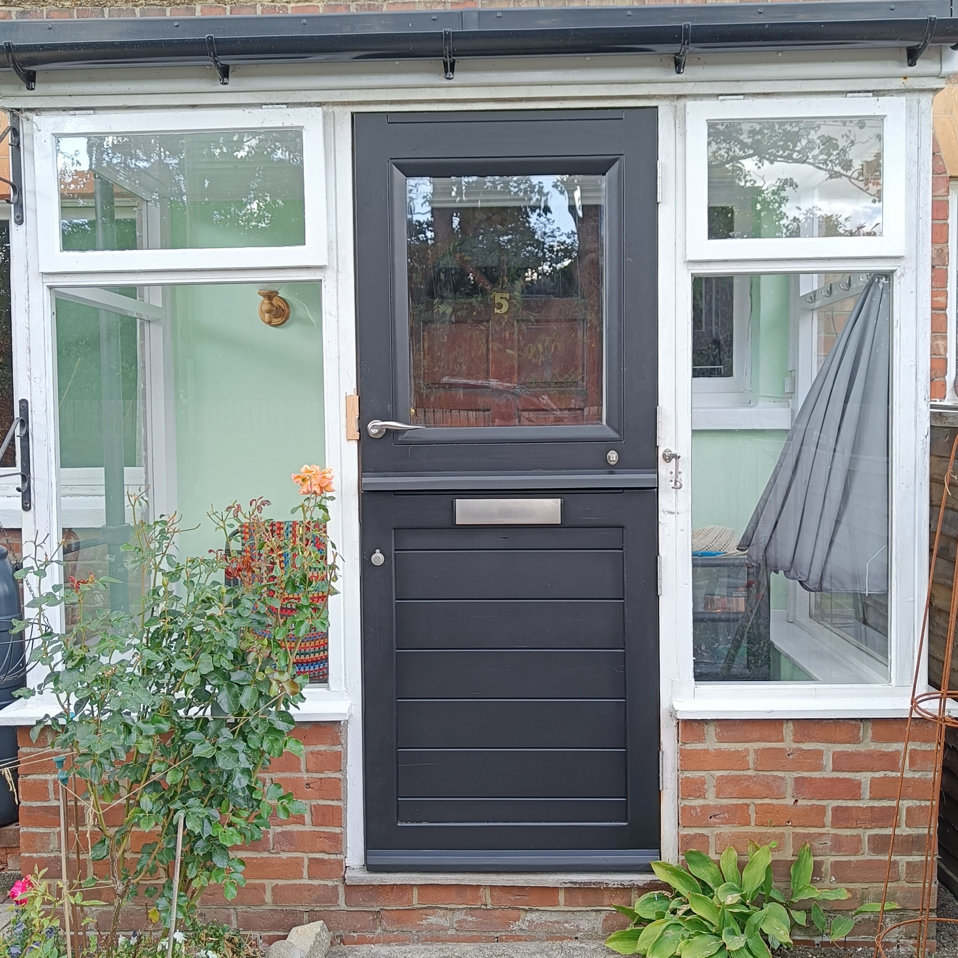 A new black wooden stable door with handle, letter box and large clear window in top door leaf